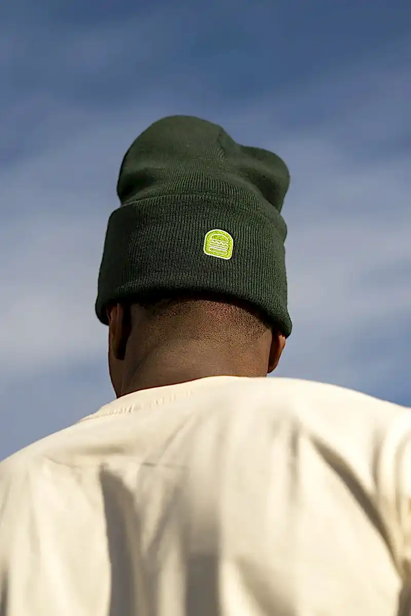 Man outside wearing green Shake Shack beanie with logo facing backwards